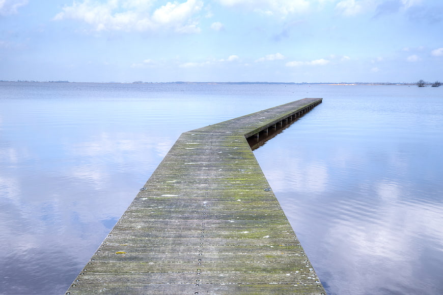 Serene wooden pier extending into calm blue lake water