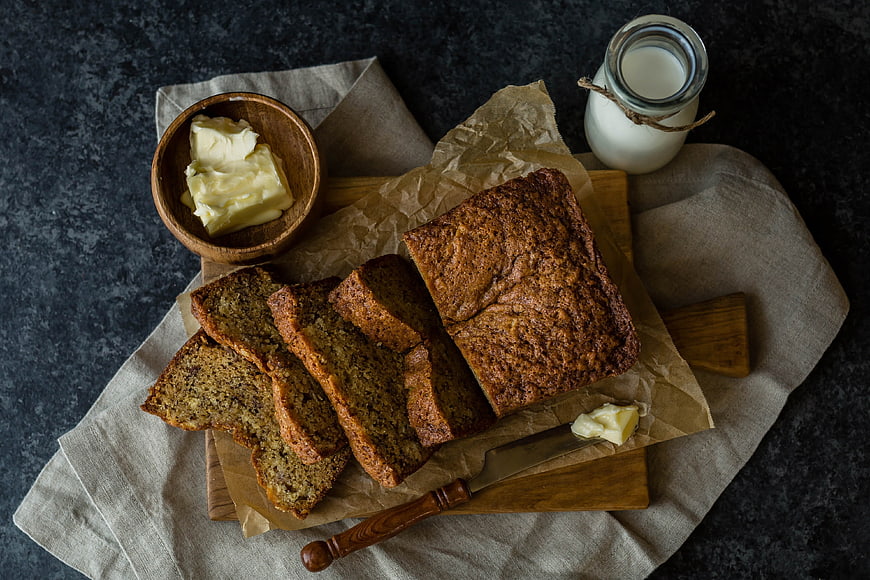 Homemade banana bread with butter and milk top view