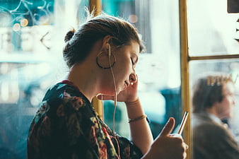 Woman Listening to Music on Smartphone in Cafe