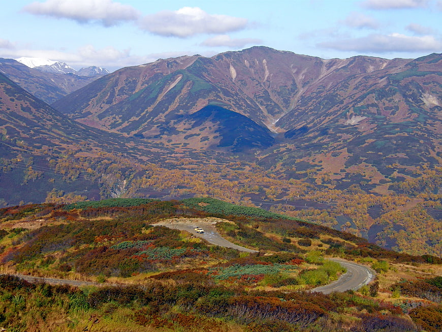 Winding mountain road through autumn landscape with distant peaks