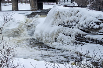 Frozen waterfall and icy river under a bridge in winter