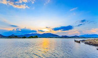 Sunset over river with canoe and mountains