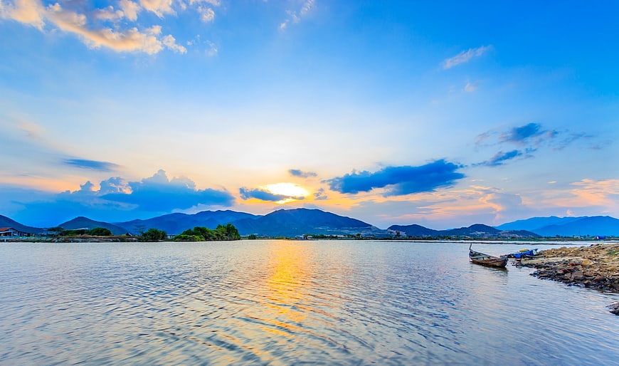 Sunset over river with canoe and mountains