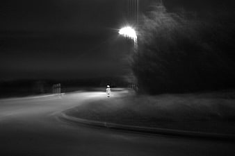 Lonely child walking on dark road at night under street light