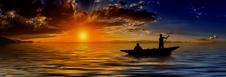 Silhouette of fishermen in a boat on the ocean at sunset