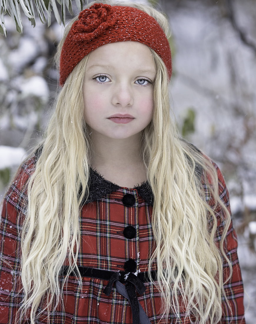 Portrait of a young girl in winter plaid coat and red headband