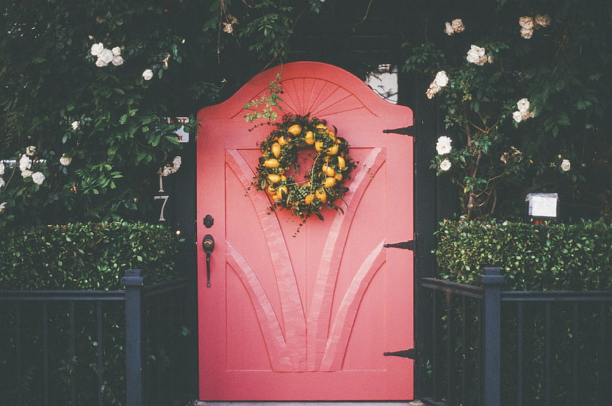 Pink arched door with lemon wreath and white roses