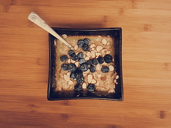 Overhead view of oatmeal with blueberries and almonds in a square bowl