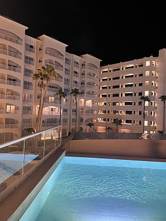 Night view of luxury hotel pool with illuminated white buildings