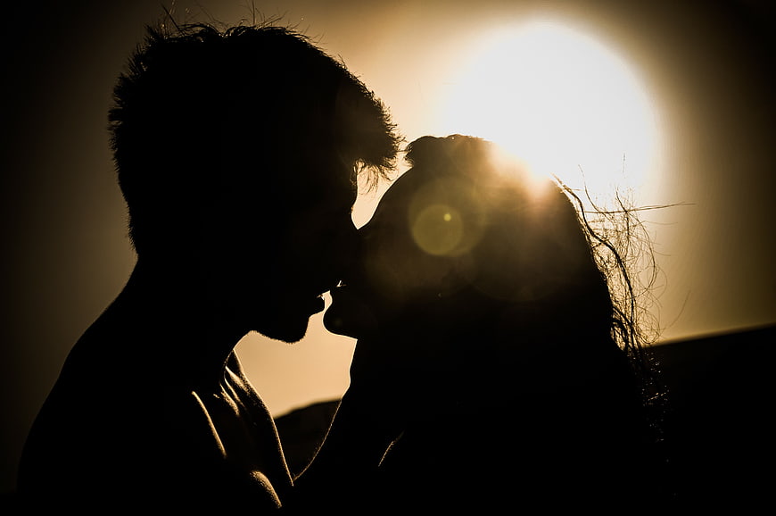 Silhouette of Couple Kissing Against Golden Sunset