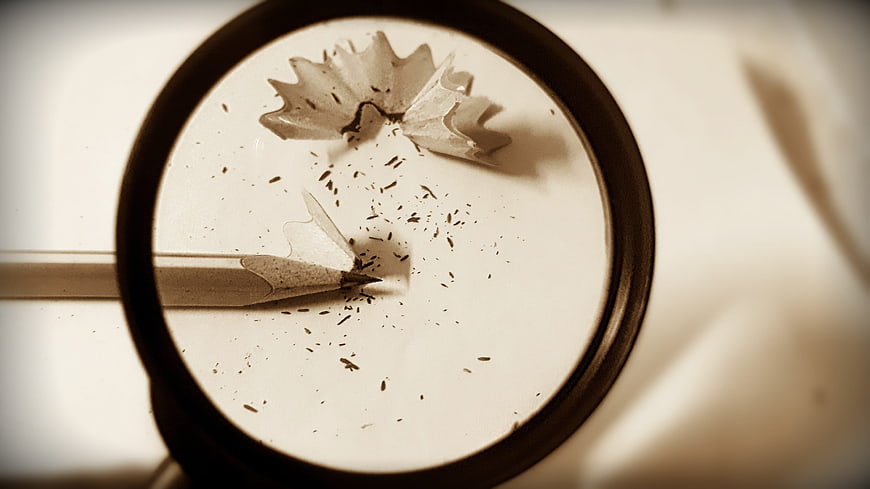 Magnifying glass over pencil shavings and graphite dust