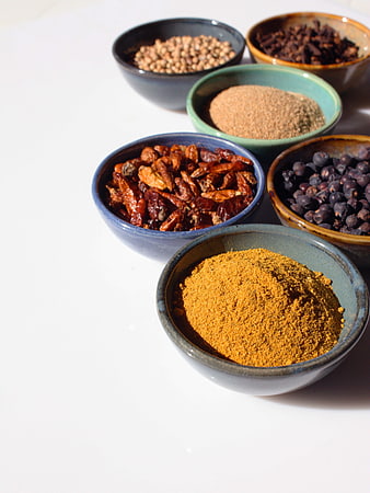 Assorted Spices and Seasonings in Ceramic Bowls on White Surface