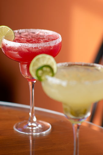 Red and Yellow Margaritas with Lime Garnish on Wooden Table