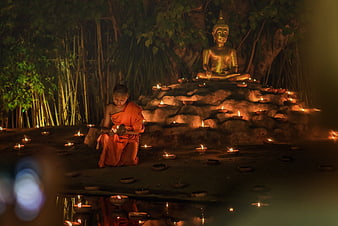 Young Buddhist Monk Praying by Candlelight at Night