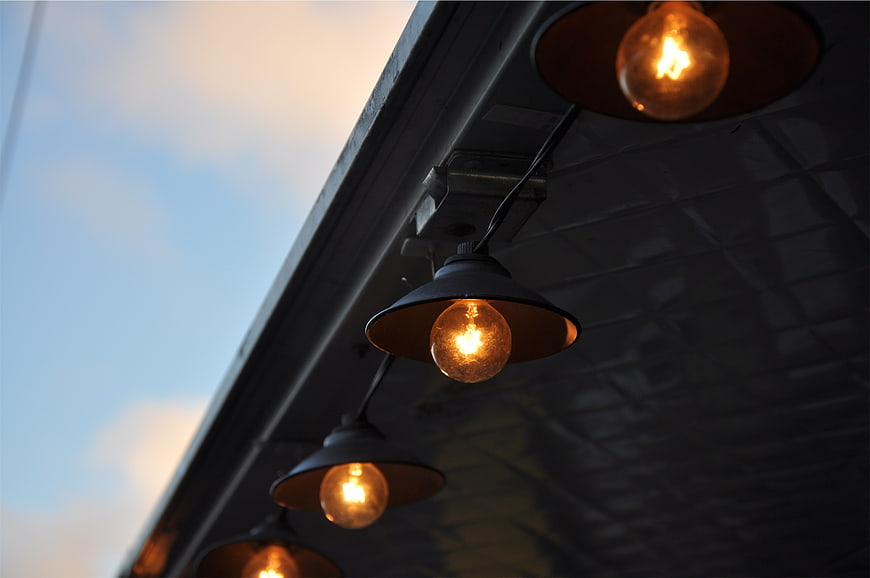 Vintage Edison Bulbs Hanging Under Awning at Dusk