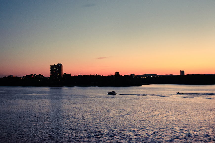 Silhouette of city skyline at sunset over water with boats