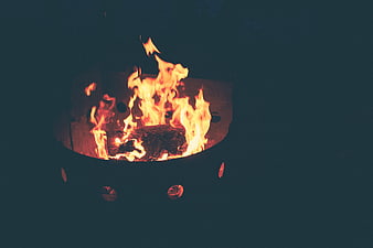 Close-up of burning wood fire in metal fire pit at night