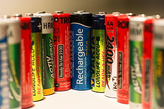 Row of colorful rechargeable AA batteries on white surface