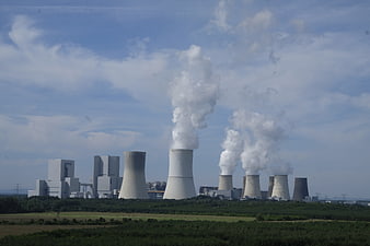 Nuclear power plant cooling towers emitting steam into blue sky