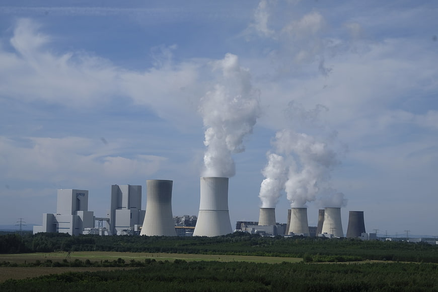 Nuclear power plant cooling towers emitting steam into blue sky
