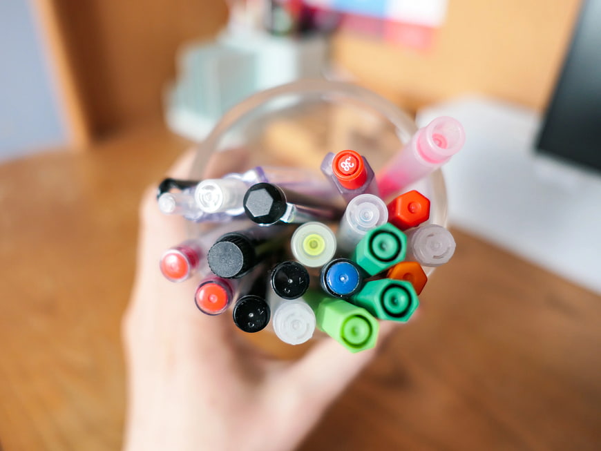 Hand Holding Colorful Markers in Glass Jar
