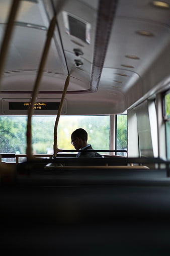 Silhouette of Boy Reading on Rainy Bus Interior