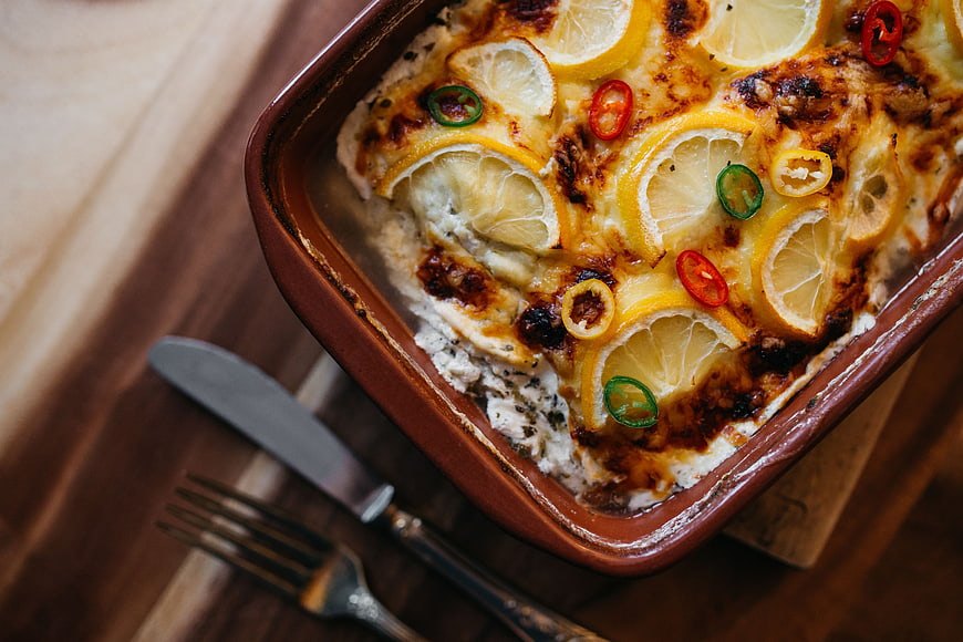 Baked fish casserole with lemon slices and chili peppers