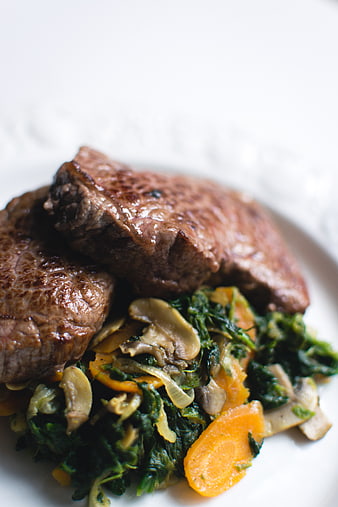 Close-up of grilled steak with sauteed vegetables on white plate