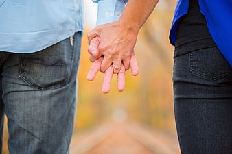 Couple Holding Hands With Engagement Ring In Autumn Field