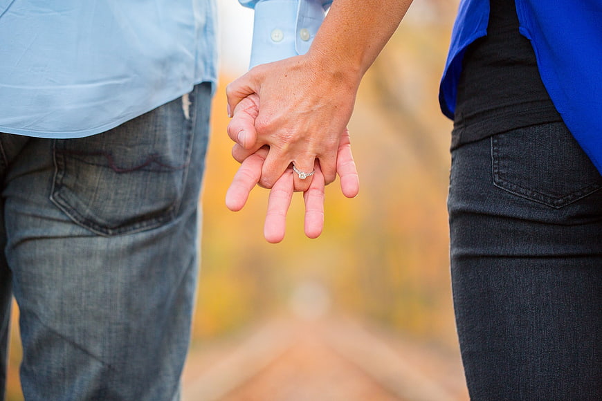 Couple Holding Hands With Engagement Ring In Autumn Field