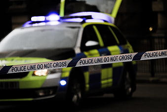 Police car with flashing lights behind crime scene tape at night