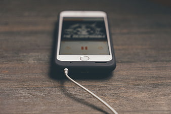 White smartphone with earphones on rustic wooden table