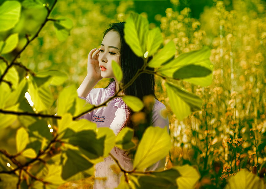 Young woman in pink dress standing in a lush green garden