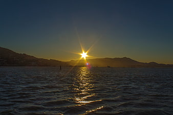 Sunset over the sea with mountains and a lone figure