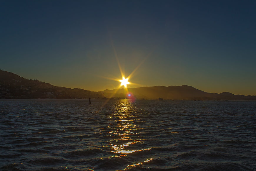 Sunset over the sea with mountains and a lone figure