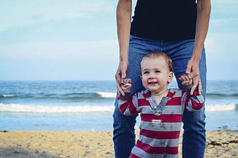 Happy Toddler Holding Parent's Hands on Sandy Beach