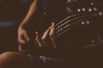Close-up of hands playing electric guitar in dim light
