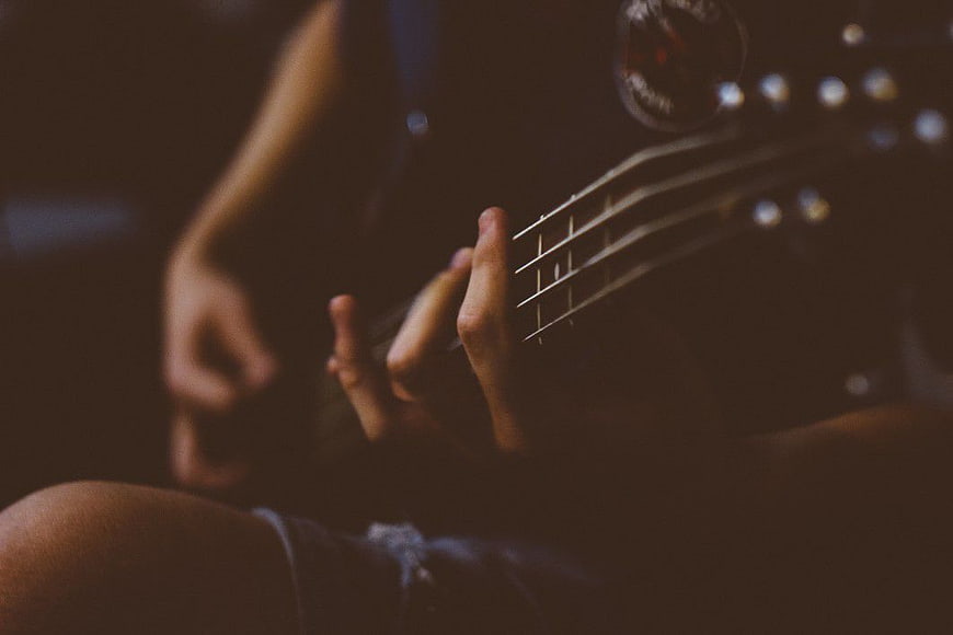 Close-up of hands playing electric guitar in dim light