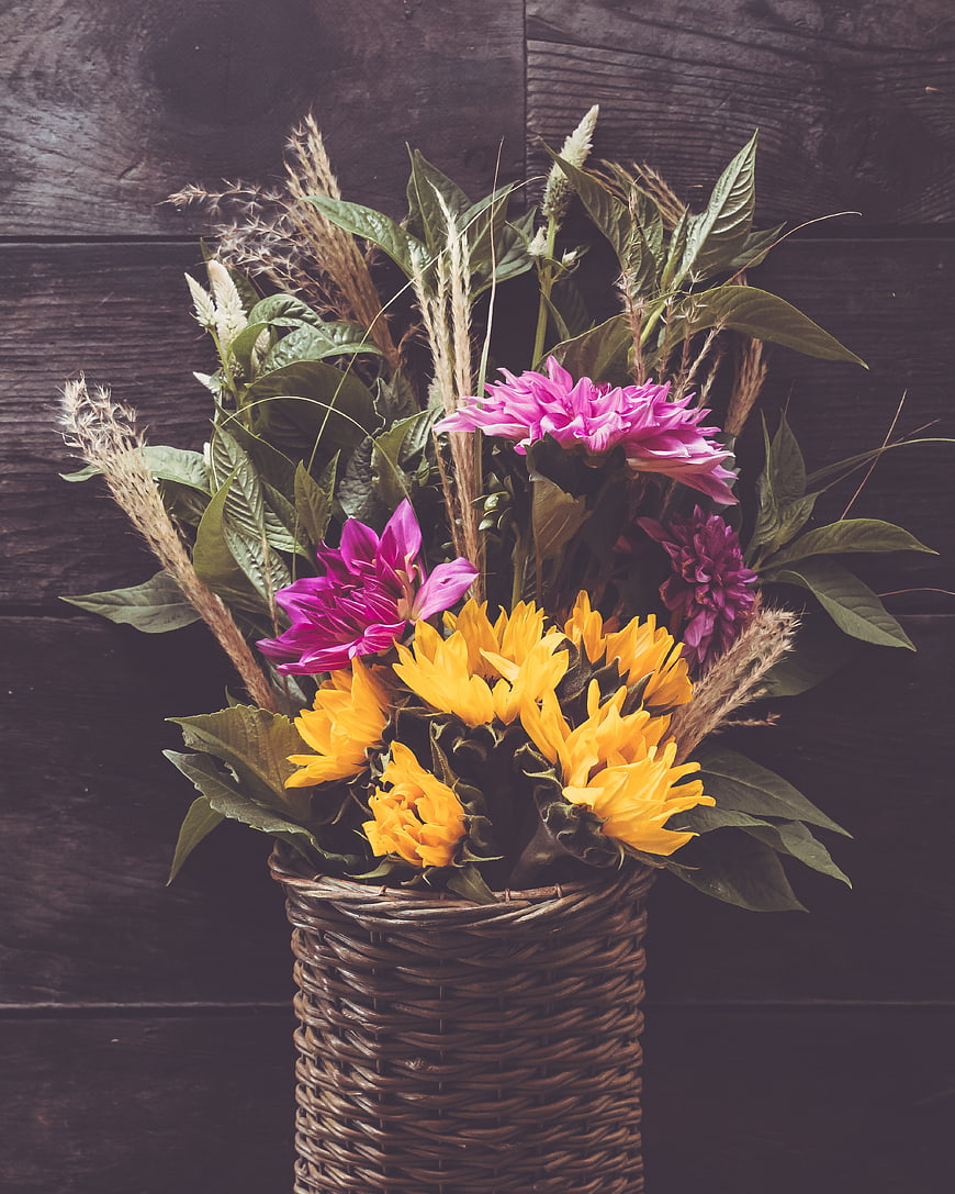 Rustic floral arrangement with yellow and pink flowers in a wicker basket
