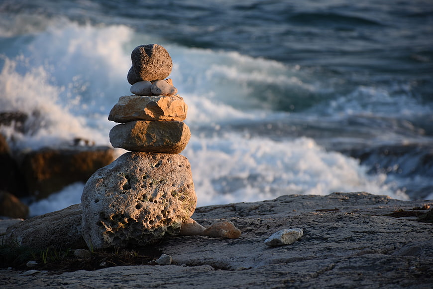 Balanced Stone Stack on Rocky Coast with Ocean Waves