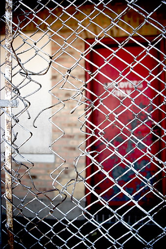Damaged Chain Link Fence with Red Door Background