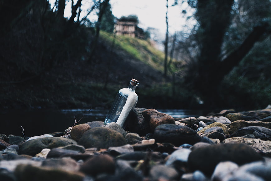 Glass bottle with message on river rocks
