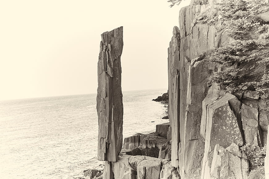 Sepia coastal cliff with vertical rock formation and ocean view