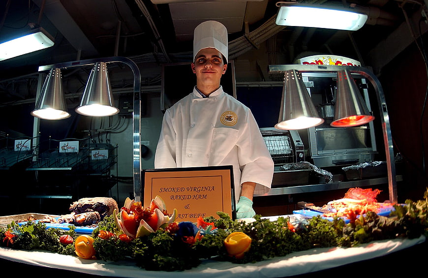 Chef standing behind buffet with smoked ham and roast beef