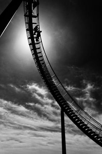 Silhouette of Roller Coaster Track Against Dramatic Cloudy Sky