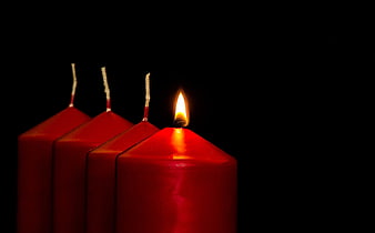 Four red candles with one lit flame on black background