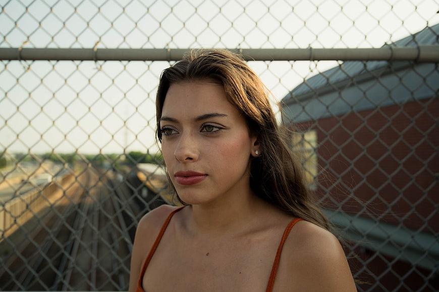 Portrait of young woman with chain link fence background