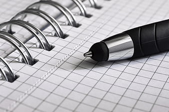 Close-up of black pen on grid notebook page