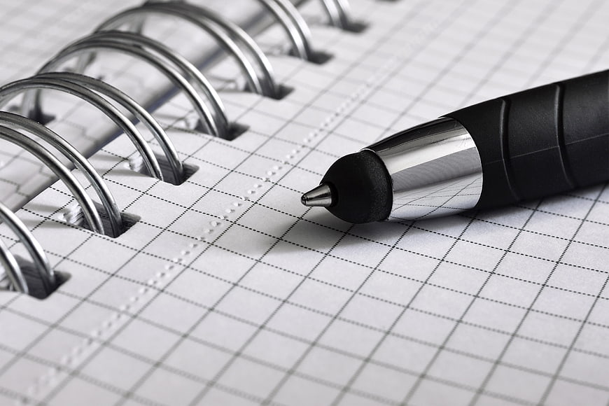 Close-up of black pen on grid notebook page