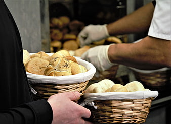 Baker serving fresh bread rolls in wicker baskets